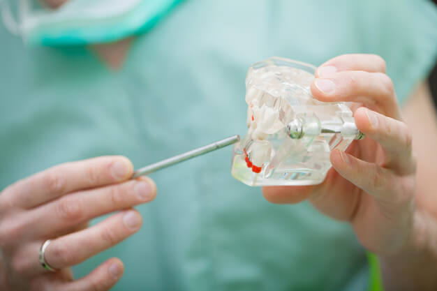 Dentista manuseando um instrumento modular: quais os cuidados antes e após uma cirurgia maxilar?