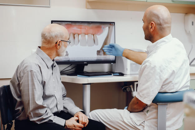 enxerto ósseo dentário dentista mostrando radiografia no computador para o paciente