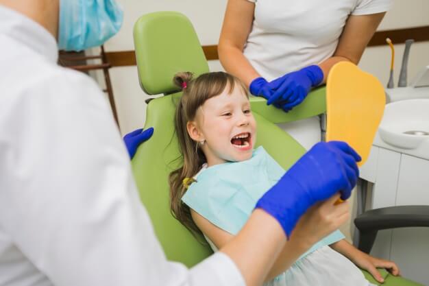 ortodontia infantil criança olhando para o espelho do dentista
