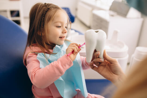 ortodontia infantil criança sorrindo olhando um dente de decoração