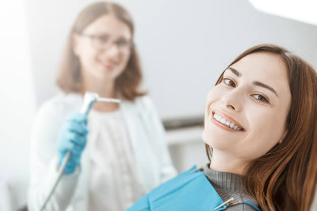 limpeza dentária dentista e paciente sorrindo no consultório odontológico