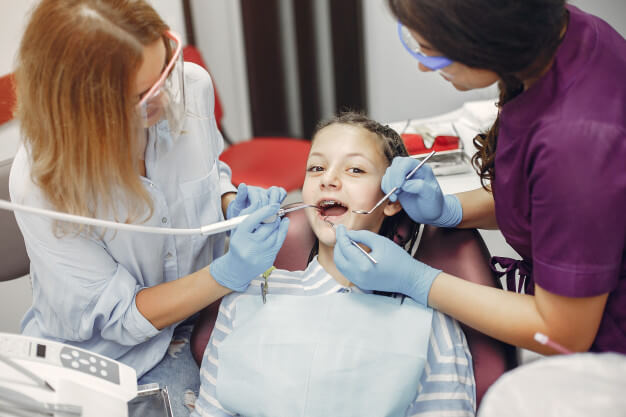 limpeza dentária profissionais fazendo tratamento em paciente criança