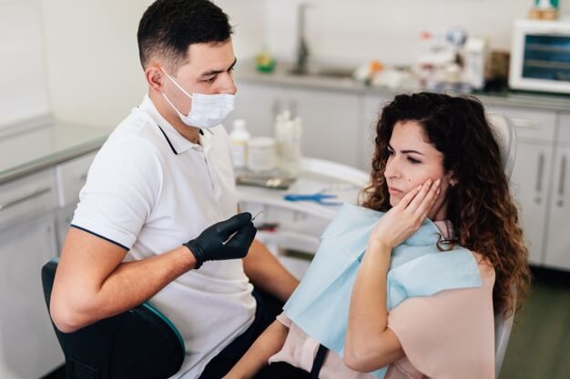 mulher quixando dor no dente inflamado para dentista
